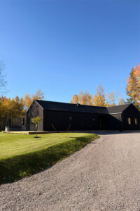 Nybyggt ladhus och enplansvilla med svart träpanel och sadeltak i Onslunda.